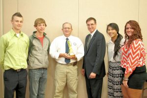 Larry Beall (center) is joined by students in receiving the Impact Award from the Iowa Energy Center.