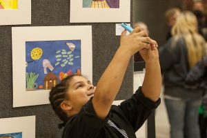 A student gets the perfect angle for a selfie with his artwork at the DMPS Art Exhibit.