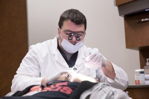 Dr. works on , the first patient to use the new dental clinic at Scavo High School.