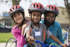 Three girls wearing bicycle helmets