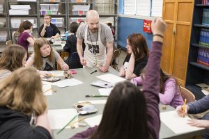 Art teacher working with students around a table