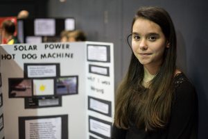 Girl standing next to science fair exhibit