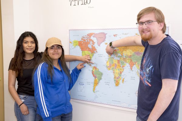 Three students point to a map.